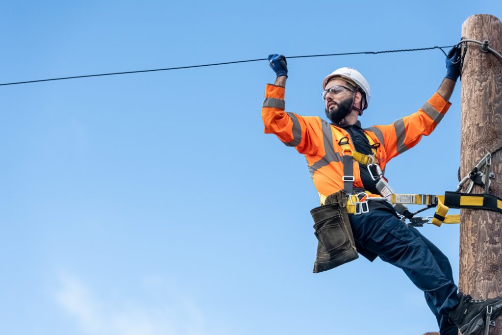 An openreach engineer with hard hat and highvis jacket installing overhead fibre cables