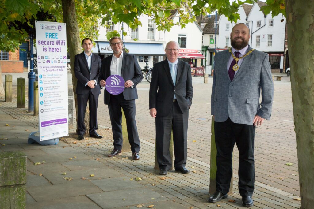 Launching free CambWifi in St Neots marketplace with pavement stickers - four male councillors staniding in the market square
