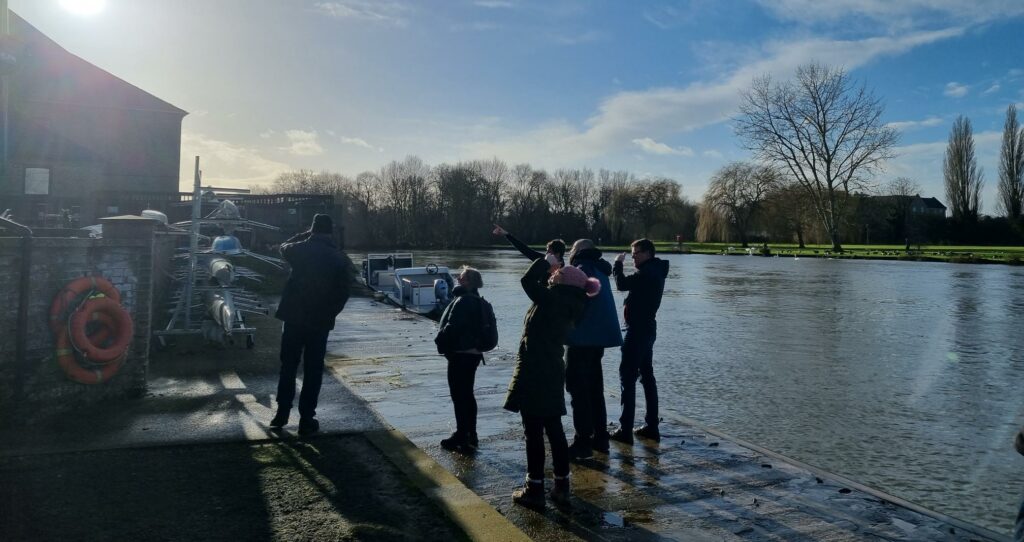 Group of people outside St Neots Rowing Club looking up at the LoRa network equipment on the club roof.