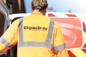 A person wearing a hi-vis Gigaclear jacket standing next to a van to indicate they are doing work to extend their fibre network