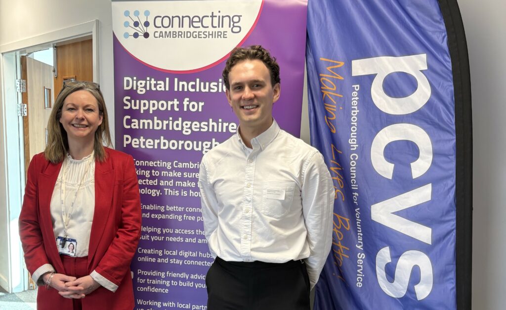 A woman and a man stand infront of two pull up banners promoting Connecting Cambridgeshire and PCVS.