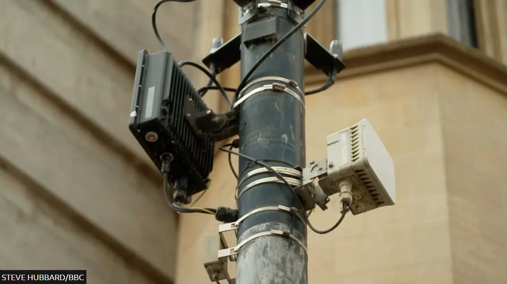 A lamppost with small cell equipment and cables attached to it.